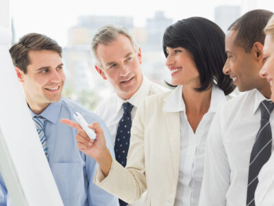 Colleagues watching happy businesswoman pointing to whiteboard in the office